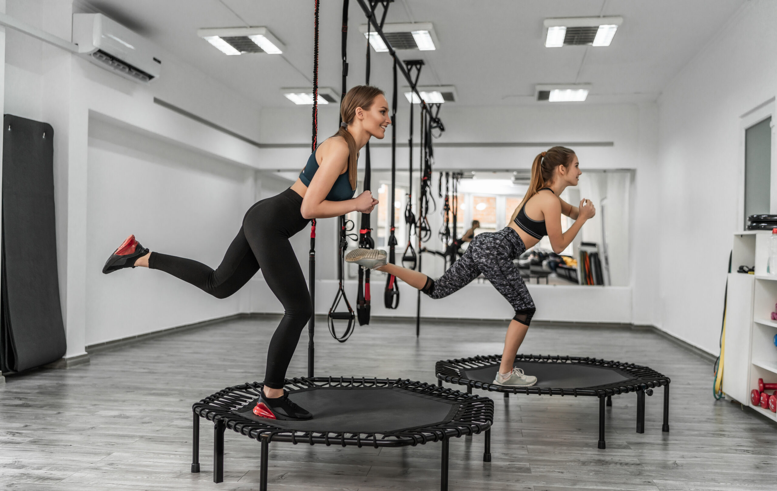 Zwei Frauen trainieren auf Mini-Trampolinen in einem Fitnessstudio