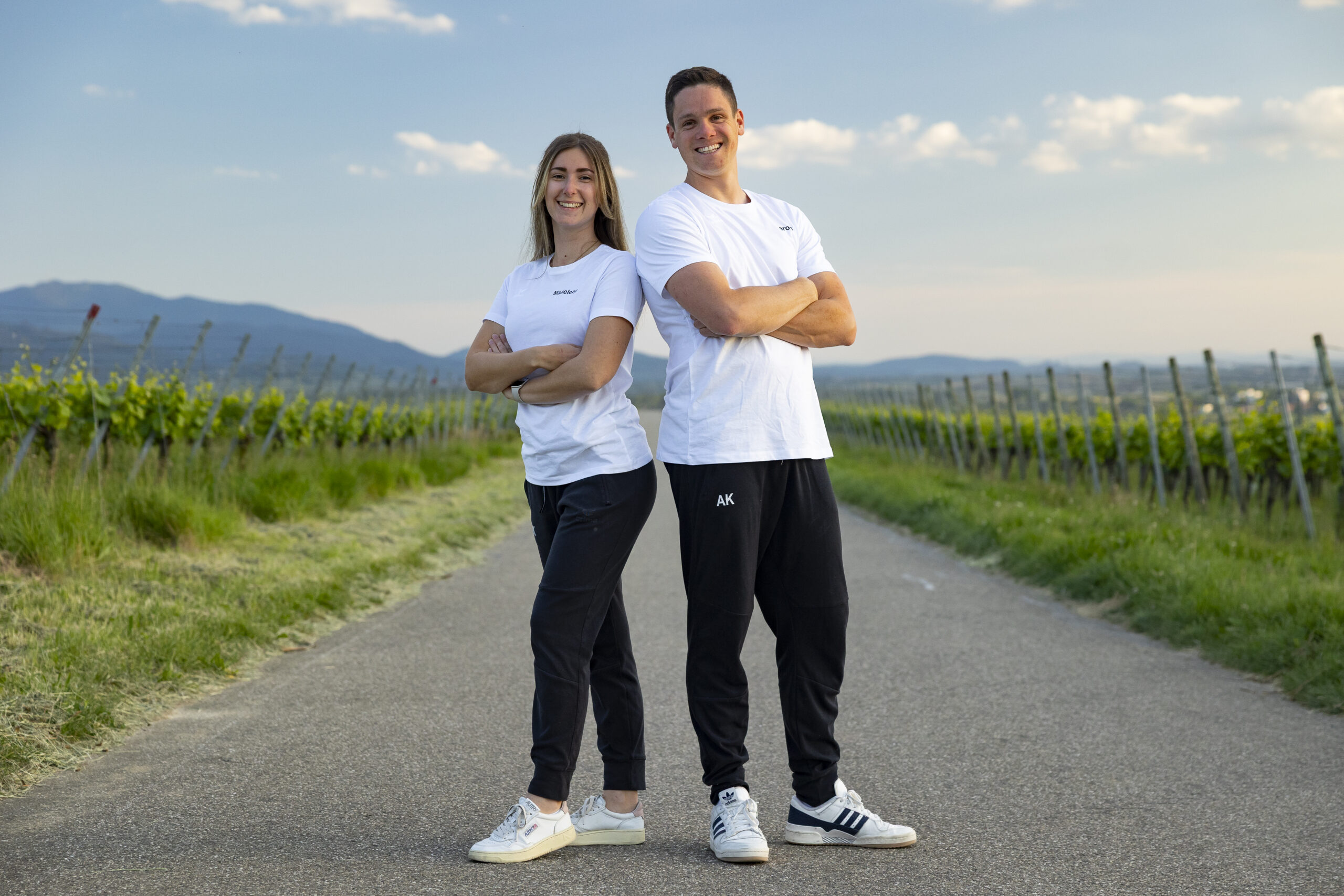 Zwei Vereinsmitglieder in weißen TV-Shirts auf einem Weg durch die Weinberge