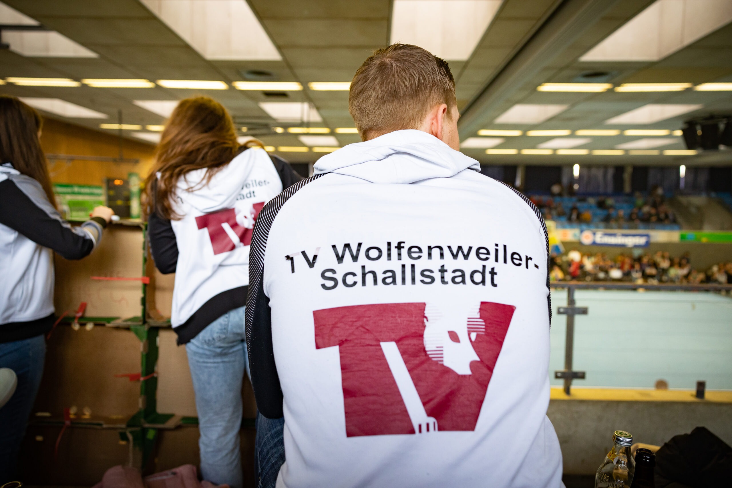 Gruppe junger Sportlerinnen und Sportler von hinten in Vereinsjacken mit Aufschrift TV Wolfenweiler-Schallstadt